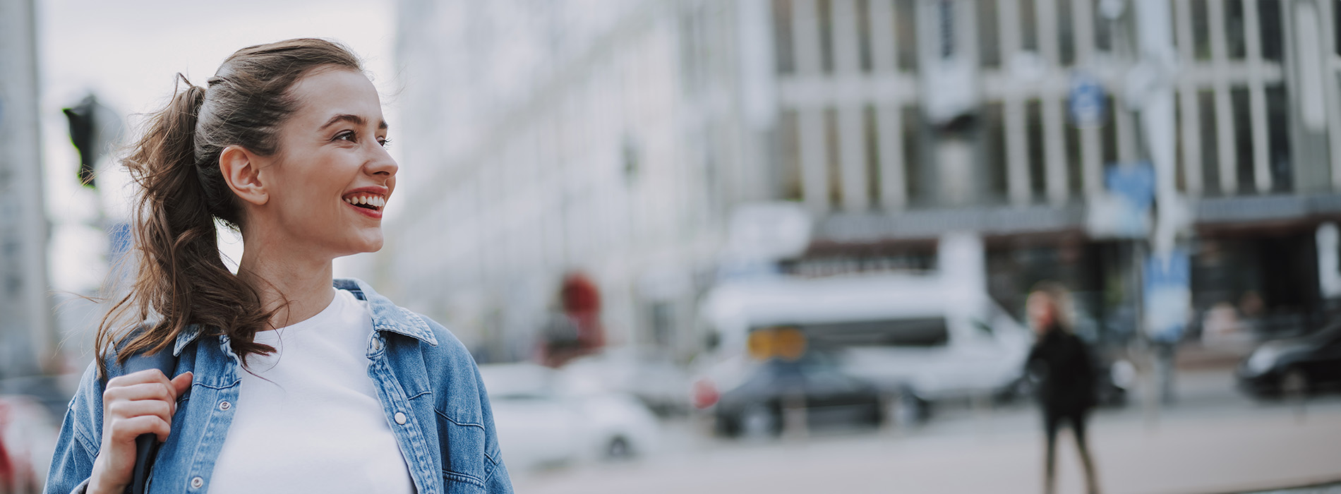 A woman in a blue jacket, smiling and posing on a city street.